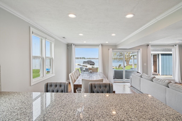 dining space with a water view, ornamental molding, recessed lighting, and wood finished floors