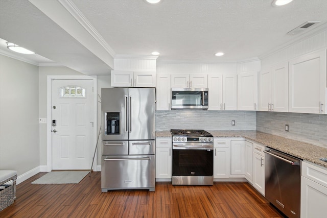 kitchen with backsplash, dark wood-style flooring, visible vents, stainless steel appliances, and white cabinetry