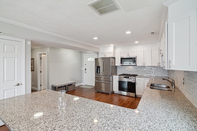 kitchen featuring a sink, backsplash, stainless steel appliances, and visible vents