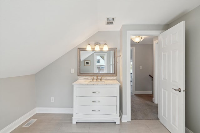 bathroom featuring vanity, baseboards, lofted ceiling, and visible vents