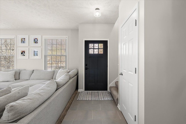 tiled foyer entrance featuring a textured ceiling and baseboards