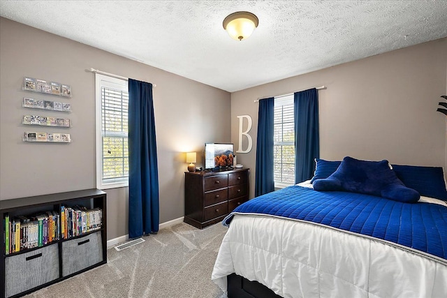 carpeted bedroom with a textured ceiling and baseboards