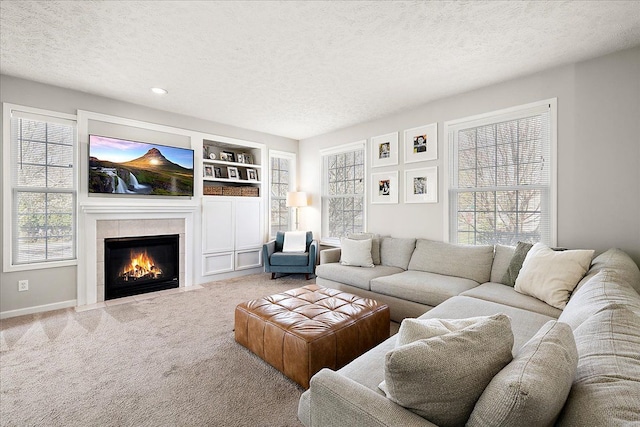 living area with a textured ceiling, a wealth of natural light, carpet floors, and a fireplace