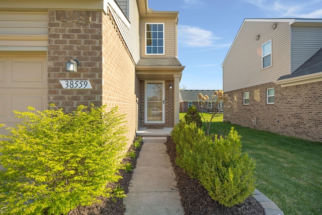 doorway to property with a yard and brick siding