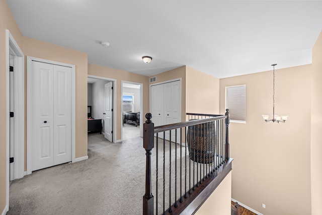 hall with baseboards, a notable chandelier, an upstairs landing, and carpet