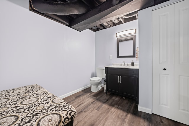 bathroom featuring baseboards, wood finished floors, toilet, and vanity