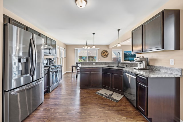 kitchen with a sink, stainless steel appliances, dark wood-type flooring, a peninsula, and dark brown cabinets
