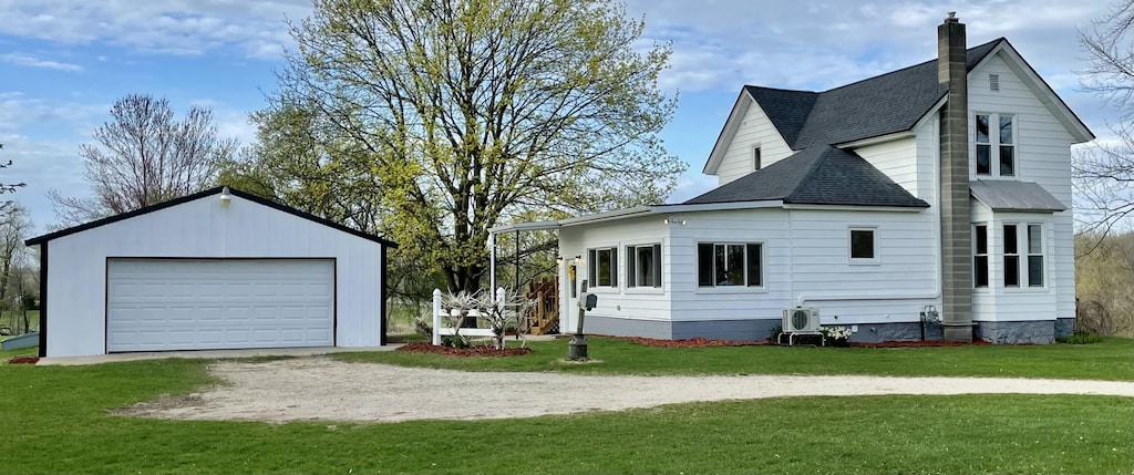 view of side of property featuring roof with shingles, a detached garage, a chimney, a lawn, and an outdoor structure
