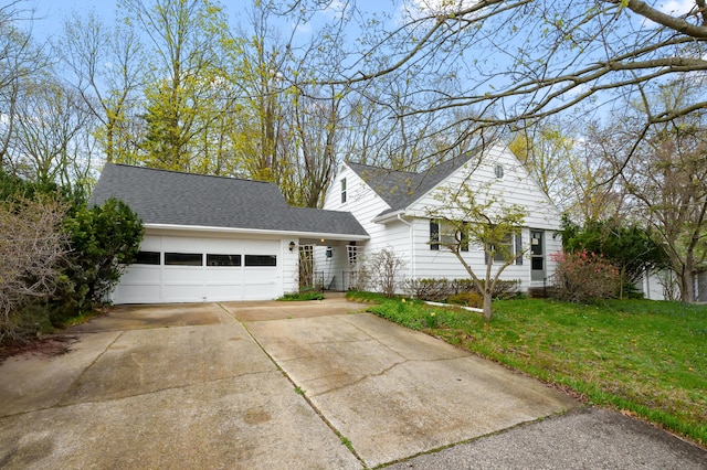 view of front of home with a front lawn, driveway, an attached garage, and roof with shingles