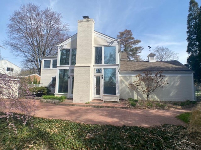 68 Davis Dr, Saginaw, MI 48602 - rear view of house with a chimney, entry steps, brick siding, and a sunroom