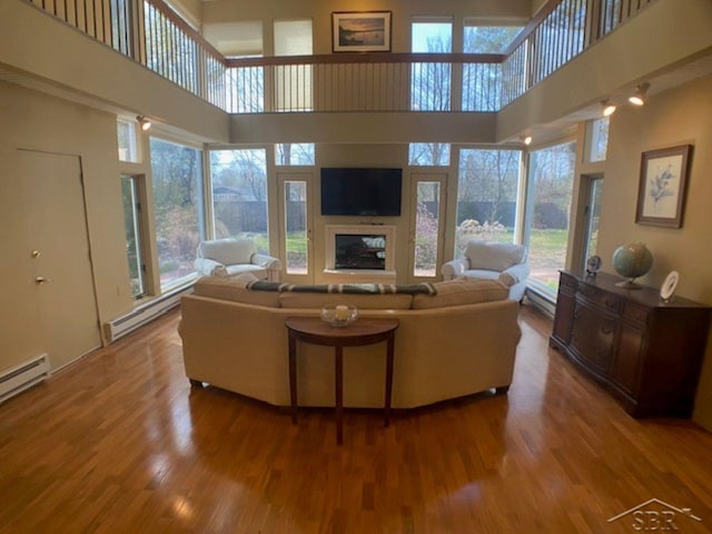 68 Davis Dr, Saginaw, MI 48602 - living area with baseboard heating, wood finished floors, a high ceiling, and a glass covered fireplace