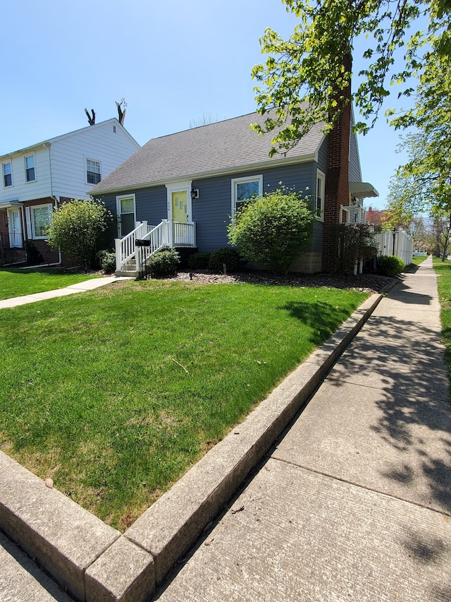 view of front facade featuring a shingled roof, a front lawn, and a chimney