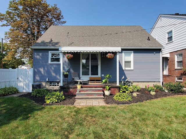 back of house featuring fence, a shingled roof, cooling unit, a lawn, and covered porch