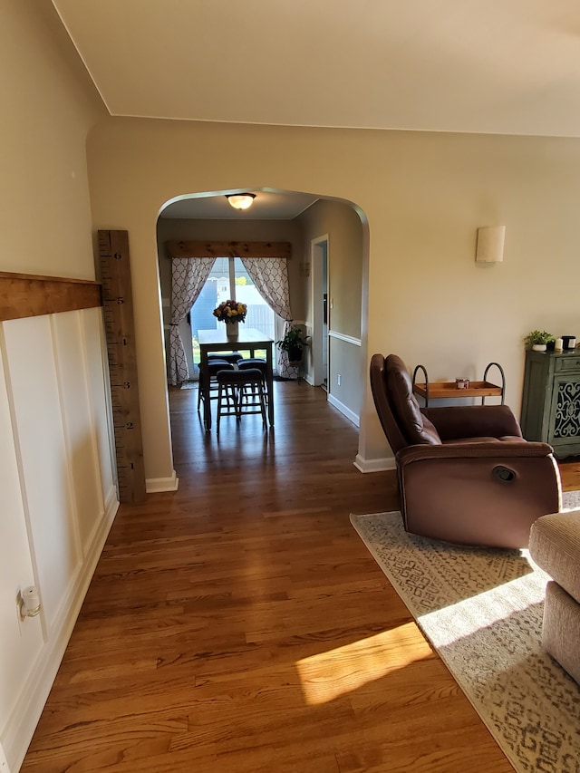 dining room with baseboards, arched walkways, and wood finished floors