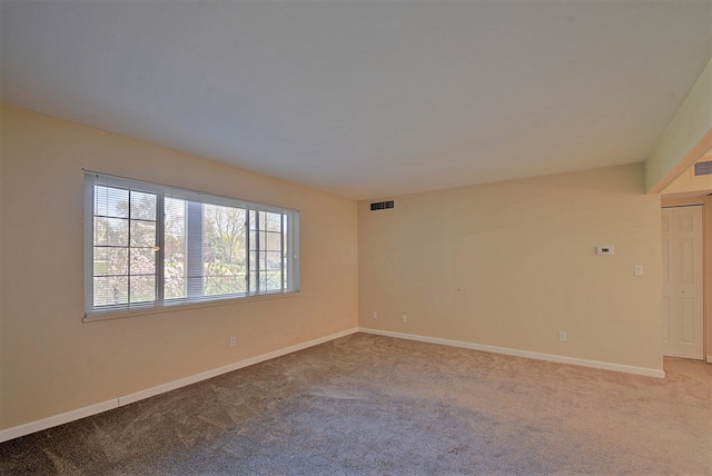 spare room featuring baseboards, light carpet, and visible vents
