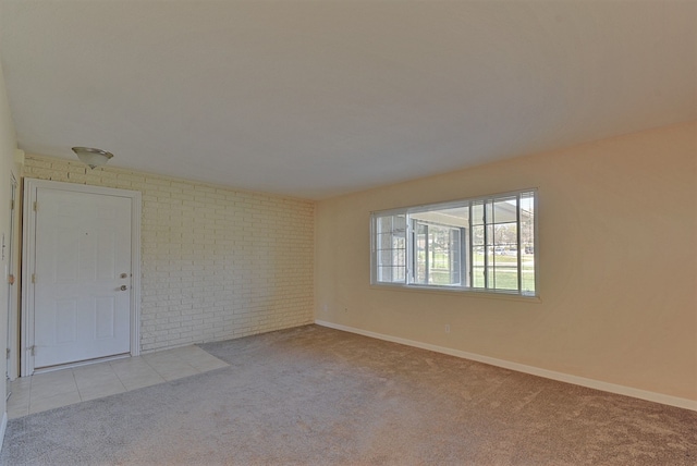 spare room featuring brick wall, baseboards, and carpet