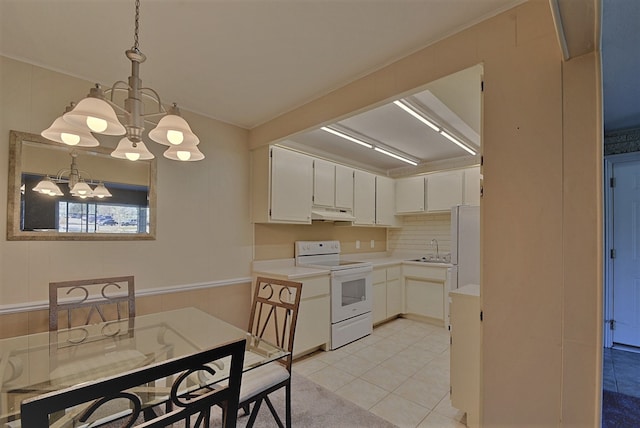 kitchen featuring a sink, light countertops, a chandelier, under cabinet range hood, and white appliances