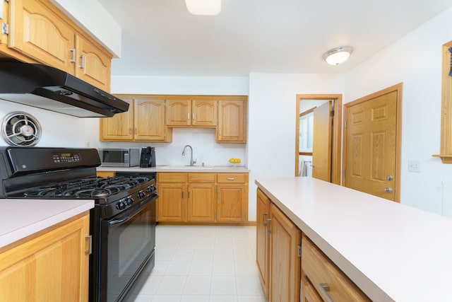 kitchen with a sink, black range with gas stovetop, light countertops, stainless steel microwave, and under cabinet range hood