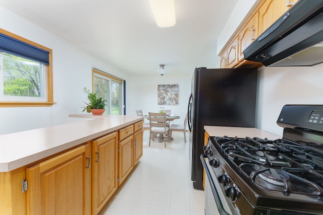 kitchen featuring under cabinet range hood, light countertops, a center island, and gas range