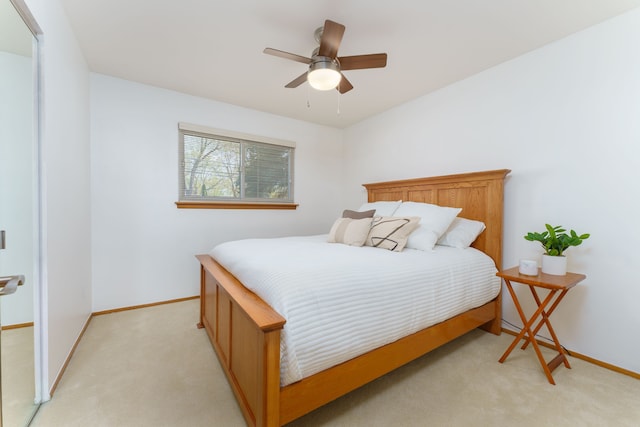 bedroom with a ceiling fan, baseboards, and light colored carpet