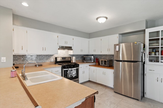 701 N Saginaw St, Durand, MI 48429 - kitchen with decorative backsplash, light countertops, under cabinet range hood, a sink, and stainless steel appliances