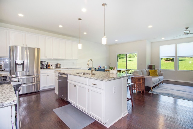 kitchen featuring a sink, backsplash, stainless steel appliances, and dark wood-style flooring