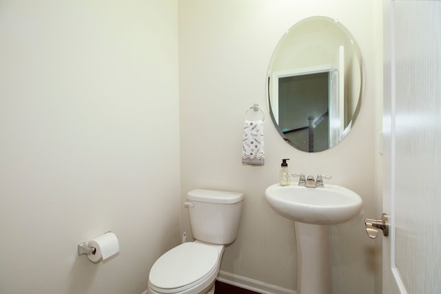 bathroom featuring baseboards, toilet, and a sink