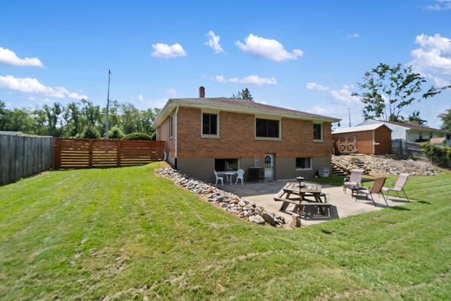 2250 Saines Manor Dr, Jackson, MI 49201 - rear view of house featuring a chimney, a fenced backyard, brick siding, a patio area, and a lawn