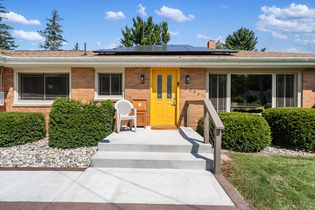 2250 Saines Manor Dr, Jackson, MI 49201 - view of front of property with solar panels, a chimney, and brick siding