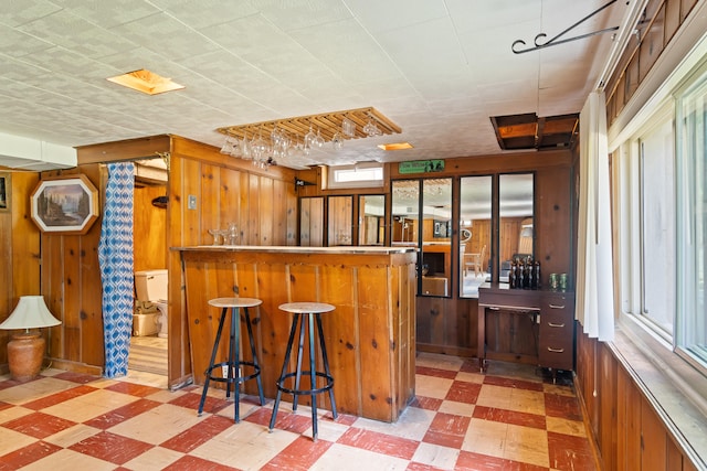 2250 Saines Manor Dr, Jackson, MI 49201 - kitchen featuring a breakfast bar area, light floors, and wooden walls