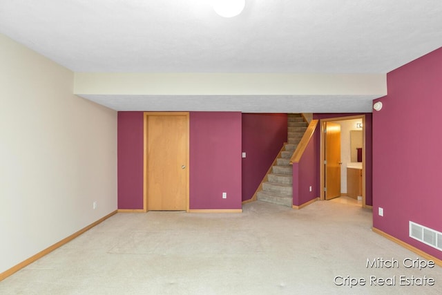 finished below grade area featuring visible vents, stairway, carpet floors, and baseboards