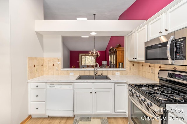 kitchen featuring white cabinetry, a sink, stainless steel appliances, light countertops, and an inviting chandelier