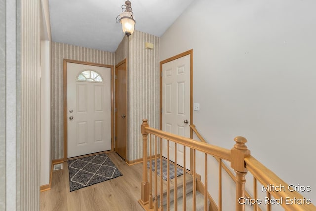 foyer entrance featuring light wood-style flooring, wallpapered walls, and baseboards