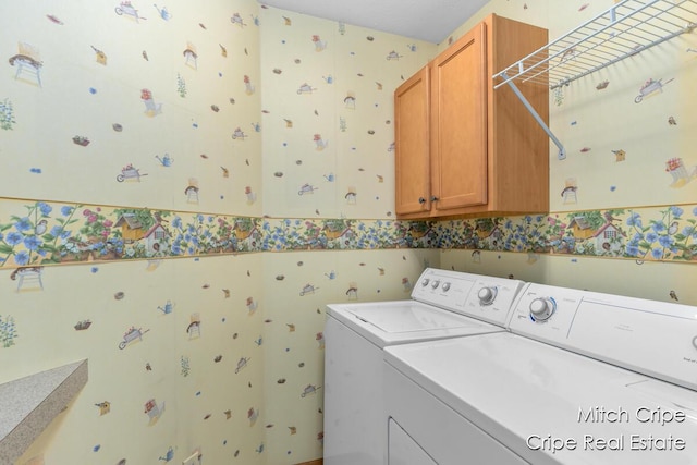 washroom featuring wallpapered walls, washer and dryer, and cabinet space