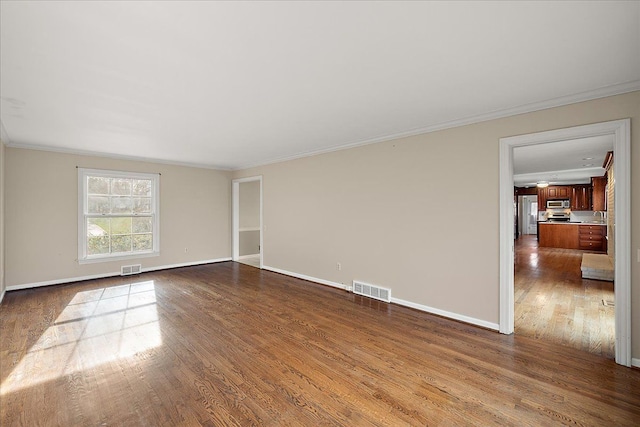 spare room featuring ornamental molding, dark wood-style floors, and visible vents