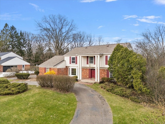 traditional-style house featuring a front yard, driveway, and brick siding