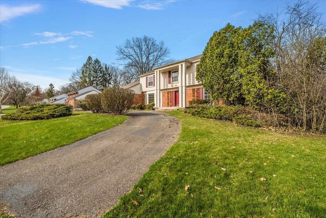 greek revival inspired property featuring driveway, a front yard, and brick siding
