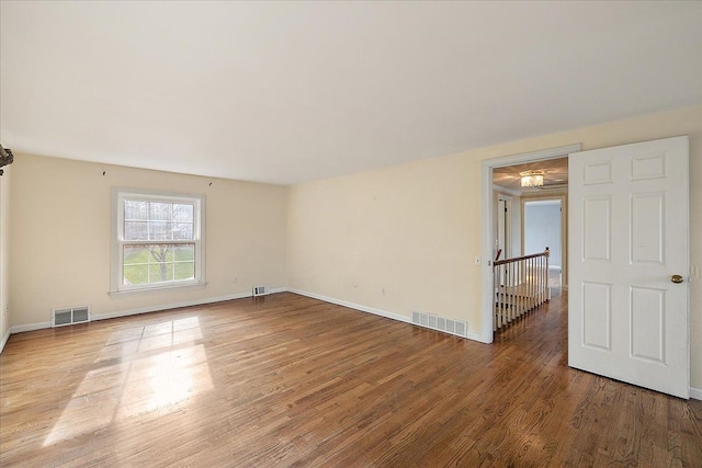 empty room with baseboards, visible vents, and wood finished floors