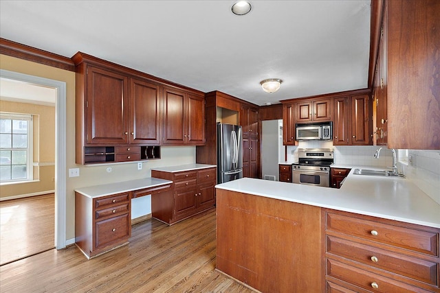 kitchen featuring light wood finished floors, a sink, appliances with stainless steel finishes, and light countertops