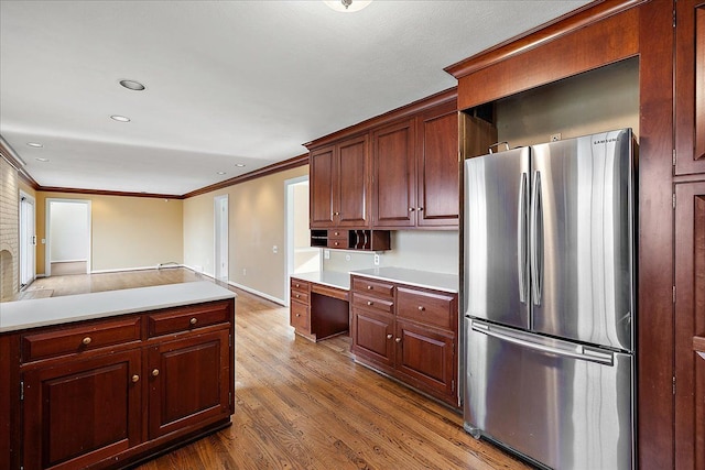kitchen featuring recessed lighting, crown molding, light countertops, freestanding refrigerator, and wood finished floors