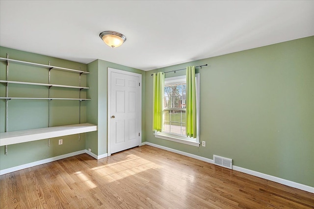 unfurnished bedroom featuring baseboards, visible vents, wood finished floors, and a closet