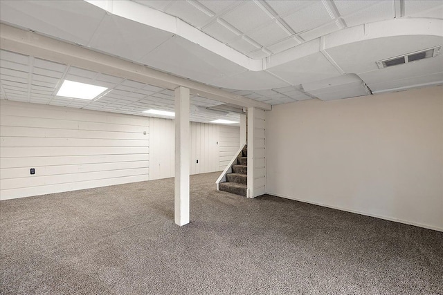 finished below grade area featuring stairway, visible vents, and carpet flooring