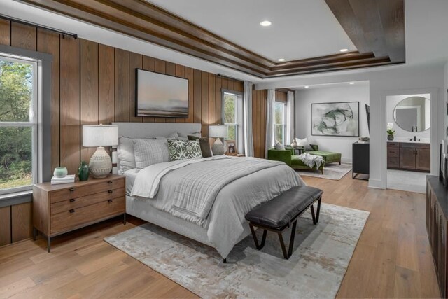bedroom with light wood-style floors, connected bathroom, recessed lighting, and a tray ceiling