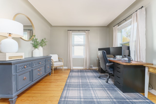 office space featuring baseboards, light wood-style flooring, and a healthy amount of sunlight