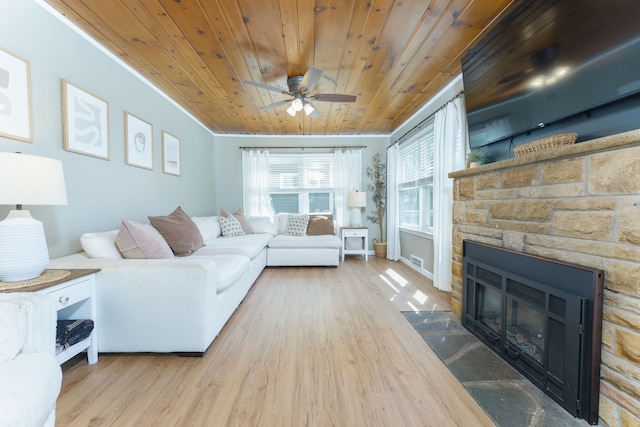 living room featuring a stone fireplace, a ceiling fan, wooden ceiling, wood finished floors, and visible vents