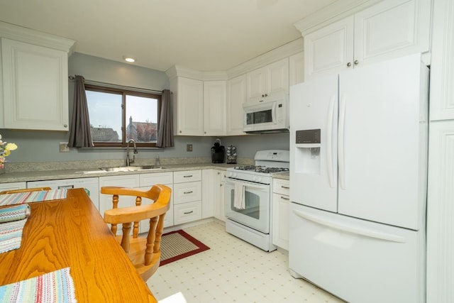 kitchen with recessed lighting, a sink, white appliances, light countertops, and white cabinets