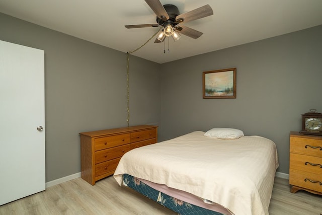 bedroom with light wood finished floors, a ceiling fan, and baseboards
