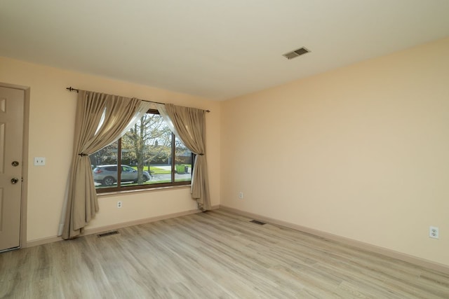 unfurnished room featuring light wood-style floors, visible vents, and baseboards