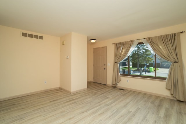 spare room featuring visible vents, baseboards, and light wood-style floors