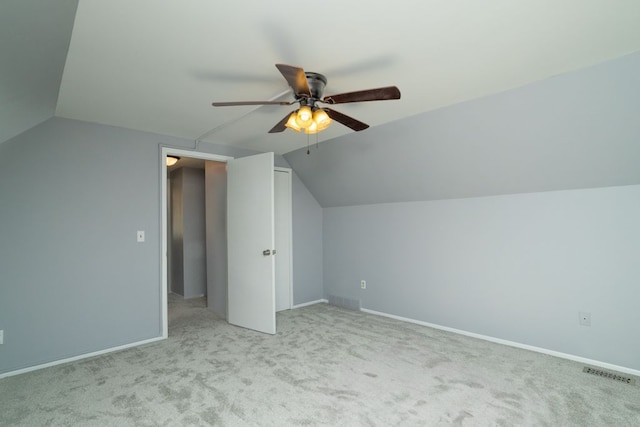 additional living space featuring light colored carpet, vaulted ceiling, ceiling fan, baseboards, and visible vents